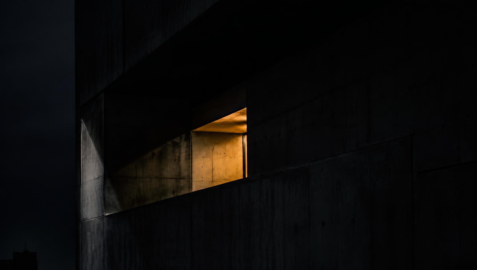 Fachada arquitectónica en concreto con una abertura iluminada